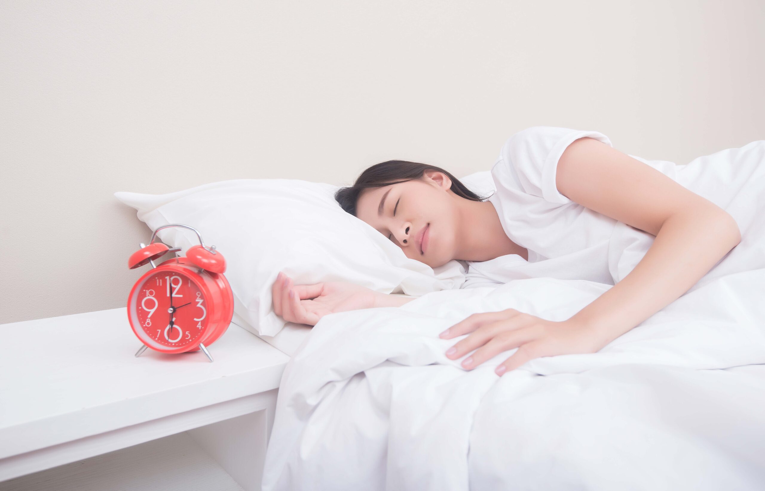 young woman sleeping bed beside alarm clock scaled